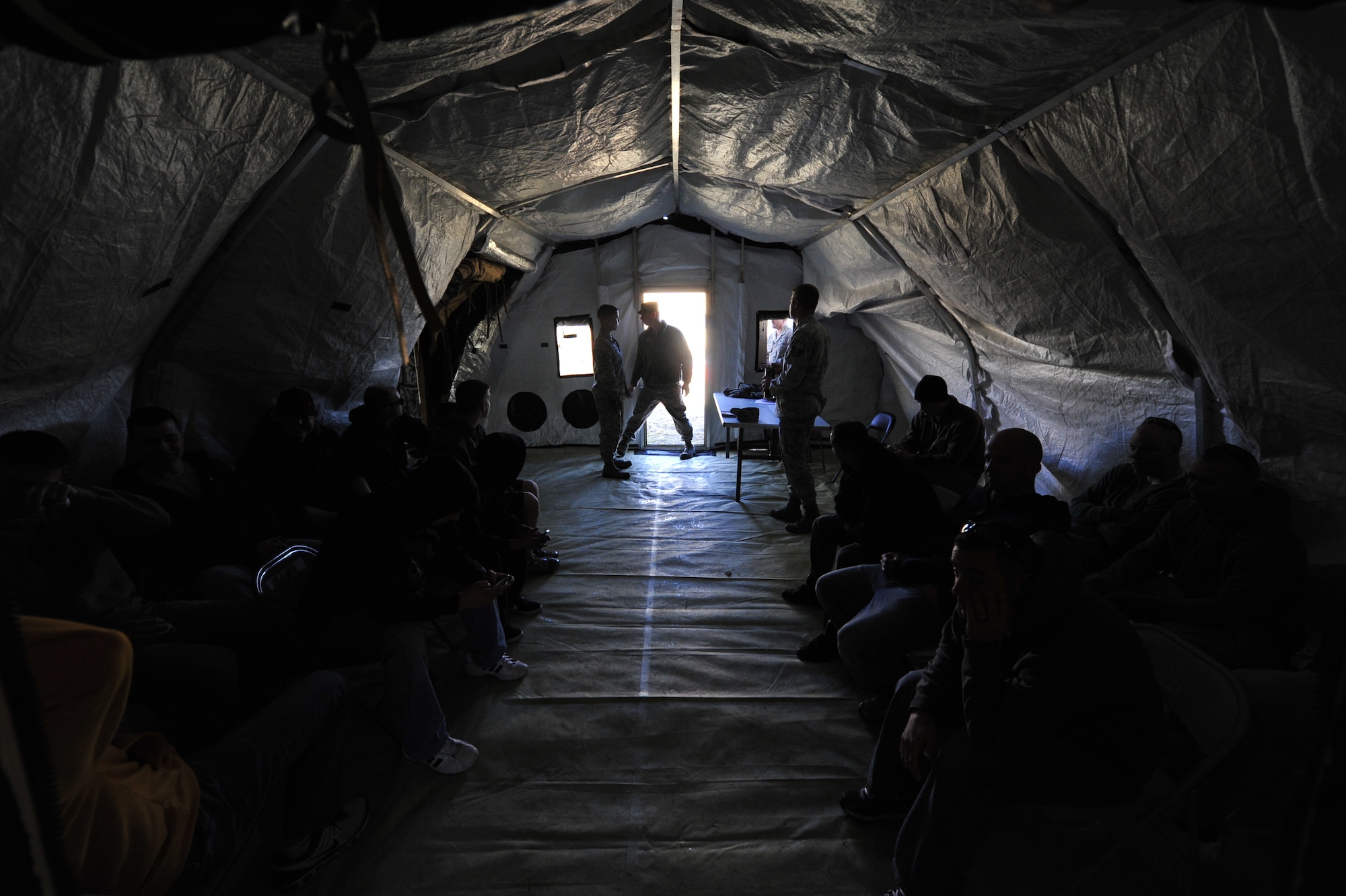 JOINT BASE MCGUIRE-DIX-LAKEHURST, N.J. – Airmen from the 621st Contingency Response Wing acting as role players wait for a flight in a holding tent during the simulated emergency evacuation of U.S. citizens ahead of a volcanic eruption here March 7. This noncombatant evacuation operation is a mission the unit has never performed, and honing these skills adds a new capability to the CRW's toolset. (U.S. Air Force photo by Tech. Sgt. Parker Gyokeres) (Released)