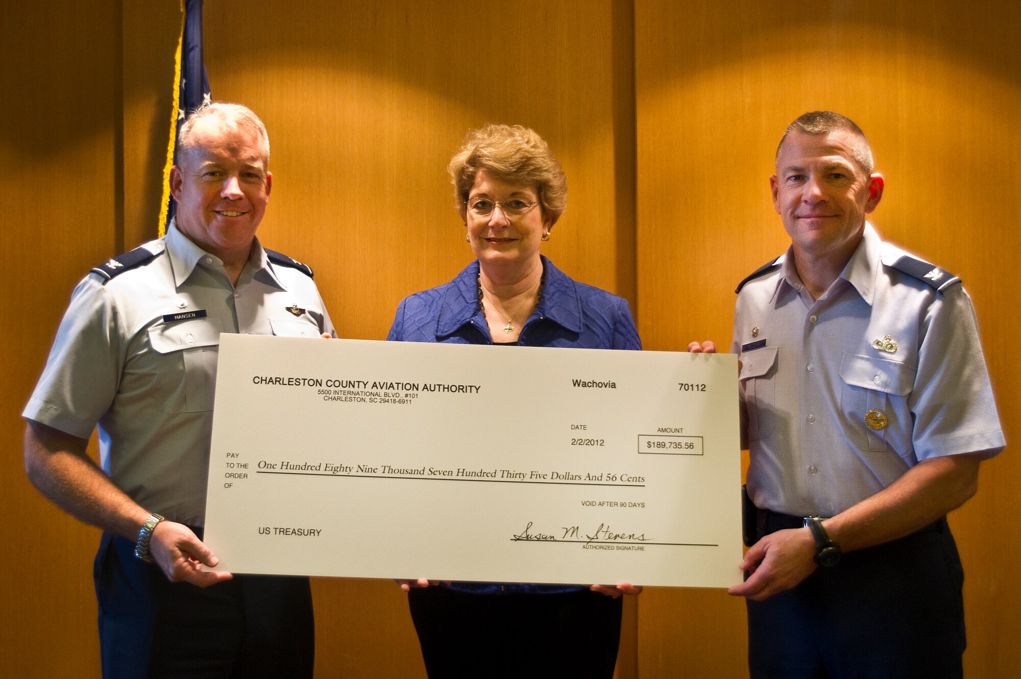 Susan Stevens presents a check for $189,735.56 for landing fees to Col. Erik Hansen and Col. Richard McComb at the Charleston International Airport, March 12. Air Force regulations stipulate that civil aircraft pay landing fees based upon the aircraft's maximum takeoff weight which is used to help maintain the runways by removing rubber buildup and painting the required runway markings. Hansen is the 437th Airlift Wing commander and McComb is the Joint Base Charleston commander. Stevens is the Charleston County Aviation Authority director of airports. (U.S. Air Force photo by Airman 1st Class George Goslin/Released)