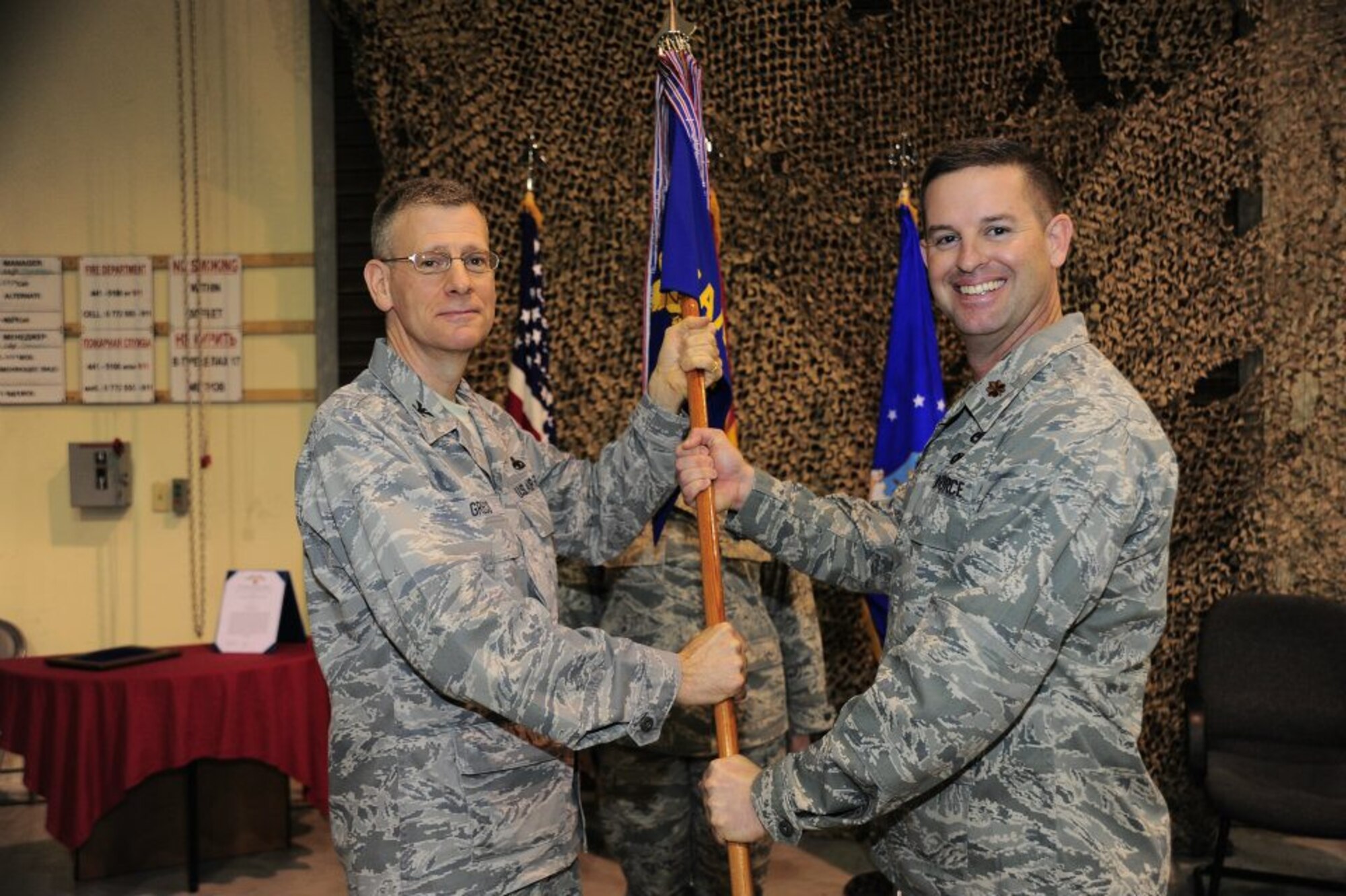 Colonel Philip Greco passes the 376th Expeditionary Aircraft Maintenance Squadron guidon to Maj. Ryan White at a change of command ceremony at the Transit Center at Manas, Kyrgyzstan March 5. Greco is the 376th Expeditionary Maintenance Group commander deployed from Gunter Air Force Base, Ala. White is deployed from the 437th Aircraft Maintenance Squadron, 437th Airlift Wing, Joint Base Charleston – Air Base.(U.S. Air Force photo courtesy 376th Expeditionary Aircraft Maintenance Squadron)