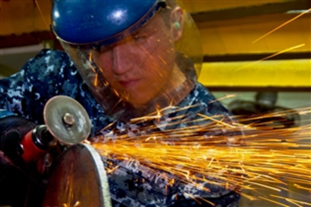 U.S. Navy Seaman Ryan Renneker grinds a blank flange for a seawater cooler on one of the diesel engines of the amphibious assault ship USS Makin Island in the Arabian Sea, March 1, 2012. The Makin Island and embarked Marines assigned to the 11th Marine Expeditionary Unit are deployed supporting maritime security operations and theater security cooperation efforts in the U.S. 5th Fleet area of responsibility. Renneker is a hull maintenance technician fireman.