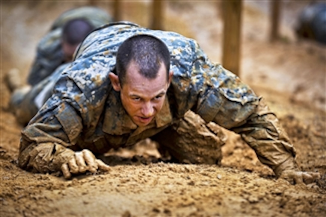 Soldiers low crawl while negotiating an obstacle course during their first week of basic combat training at Fort Benning, Ga., on March 9, 2012.  