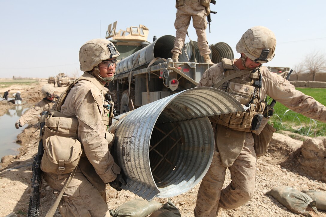 Marines with Engineer Support Company Detachment, 9th Engineer Support Battalion, 1st Marine Logistics Group (Forward) carry a culvert into place, March 14. The culvert is a tunnel built under a bridge that allows water to pass.