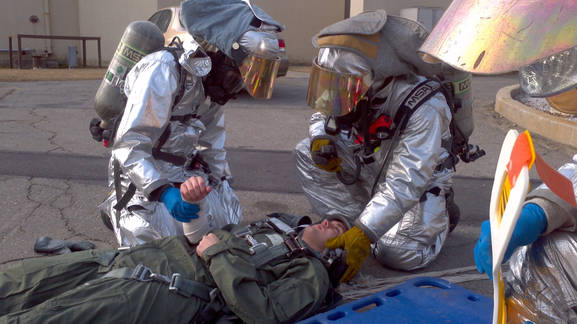 Firefighters assist a pilot of a simulated aircraft accident on Kunsan Air Base, Republic of Korea, March 14, 2012. As part of the exercise, the pilot was found with injuries sustained from an erratic parachute landing as a result of the crash. Airmen were tested on their abilities to quickly respond to the incident, which occurred near the wing headquarters building. (U.S. Air Force photo by Senior Airman Jessica Hines/Released)
