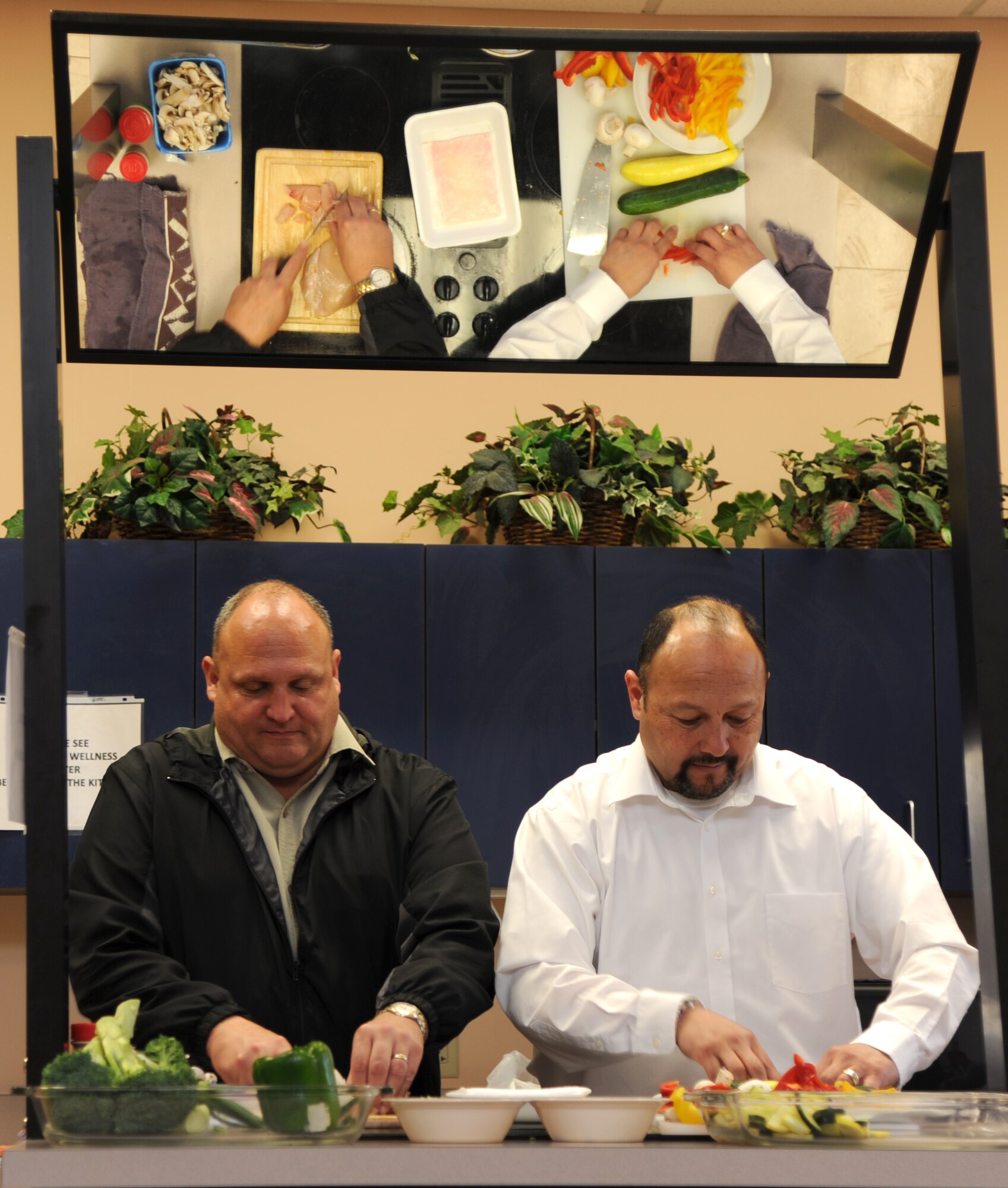 Chris Christopherson, left, and Angel Dominguez demonstrate tips and tricks for preparing chicken stir fry with vegetables during a cooking class for single Airmen, March 12, at Vance Air Force Base, Okla. (U.S. Air Force photo/ Airman 1st Class Frank John Casciotta)