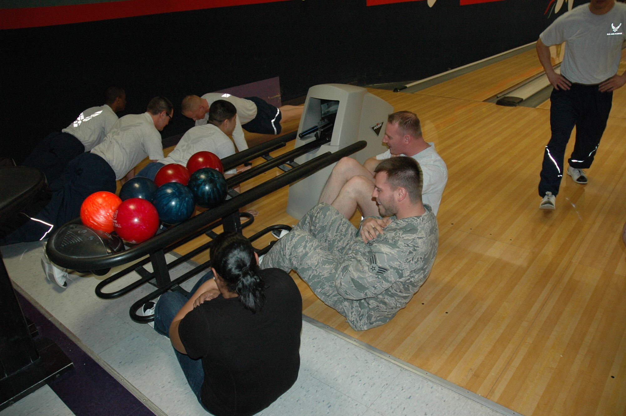 Members of the 375th Operations Support Squadron do pushups and sit-ups between bowling games. The Combat Bowling program offers a change of pace to the Air Force PT program. (Courtesy photo) 