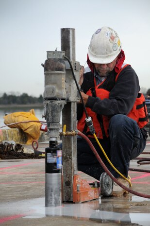 Russel Windham, a contractor with Advanced Concrete Cutting, drills holes into concrete during the deconstruction of pier Charlie at Joint Base Charleston-Weapons Station, March 13. The holes will be used as anchoring points for a crane to lift sections of the pier. Pier Charlie is being demolished as part of a program to remove excess infrastructures. Once Pier Charlie is dismantled, workers will build a smaller pier to allow Harbor Patrol Units access to the 628th Logistics Readiness Squadron Port Operations Facility.  (U.S. Navy photo/Petty Officer 1st Class Jennifer Hudson)