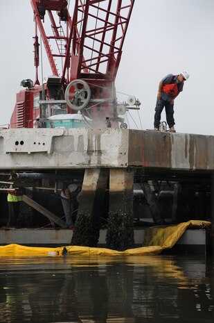 Workers cut piping from below while other workers use a concrete wire saw to prepare sections pier Charlie to be lifted by crane at Joint Base Charleston-Weapons Station, March 13. Pier Charlie is being demolished as part of a program to remove excess infrastructures. Once Pier Charlie is dismantled, workers will build a smaller pier to allow Harbor Patrol Units access to the 628th Logistics Readiness Squadron Port Operations Facility.  (U.S. Navy photo/Petty Officer 1st Class Jennifer Hudson)