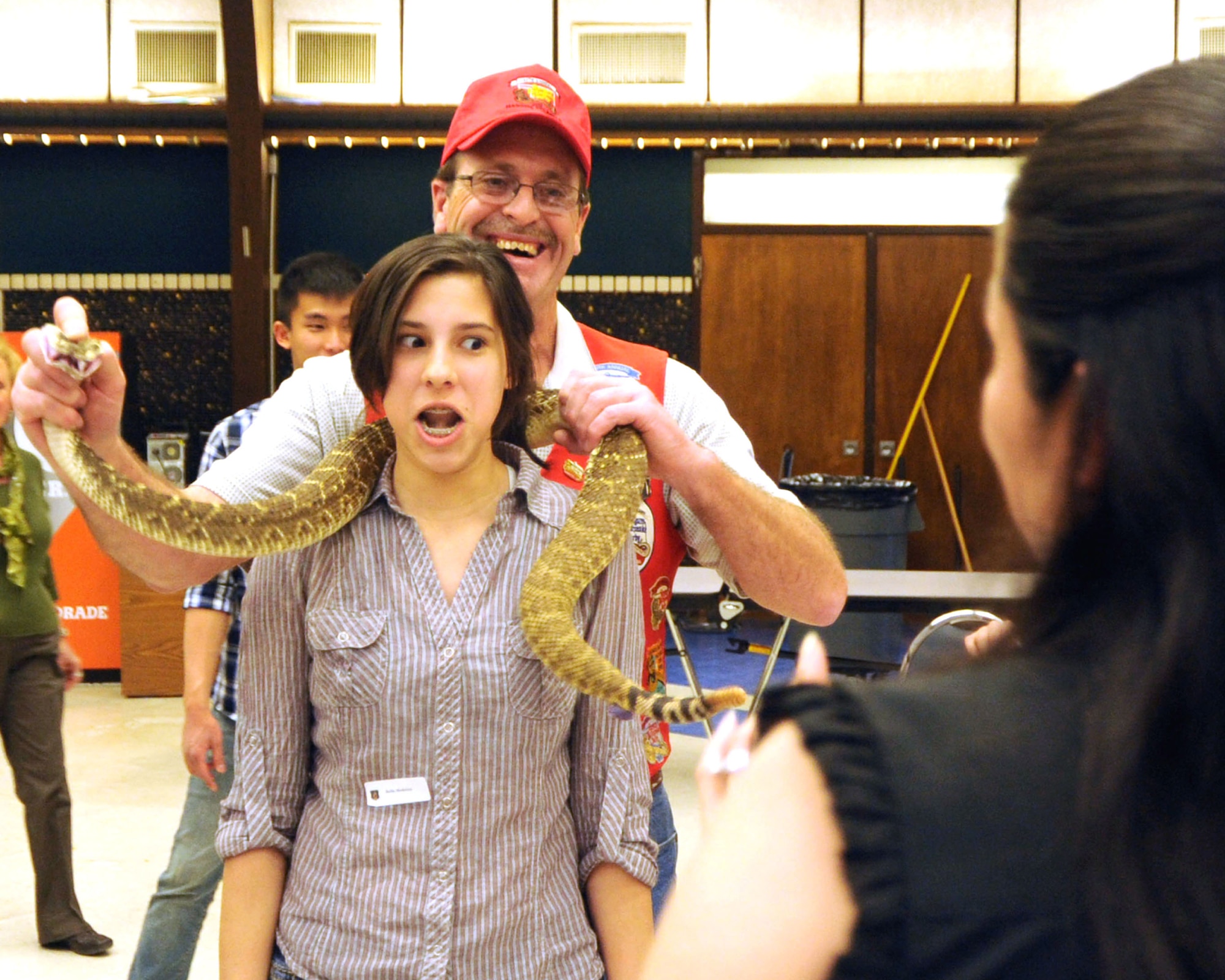 ALTUS AIR FORCE BASE, Okla. – Gabrielle Medina stands still as Fangmaster Keith Kendall drapes a rattlesnake around her neck at the Committee of 100 dinner March 12, 2012, while her mother, Major Olga Acosta, 97th  Comptroller Squadron commander, prepares to take her picture. The Committee of 100 is an Altus organization that has been hosting events for Airmen new to Altus, those returning from a deployment and students assigned to Altus AFB for training since 1984. (U.S. Air Force photo by Senior Airman Myles T. Stepp / 97th Air Mobility Wing Public Affairs / Released)