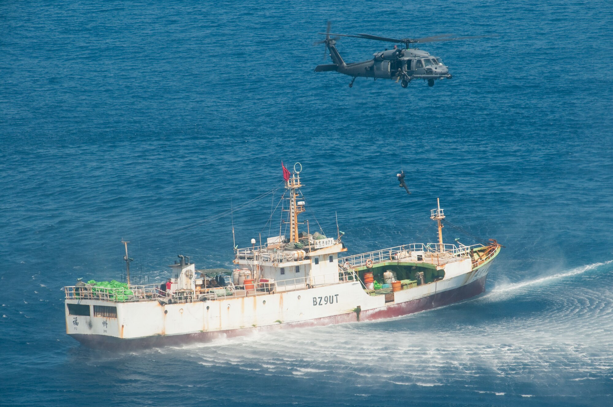 An HH-60G Pave Hawk rescue helicopter from the 129th Rescue Wing hovers over the Chinese fishing vessel Fu Yuan Yu #871, March 12, 2012. Guardian Angel Pararescuemen from the wing rescued two fishermen who were burned in a diesel fire onboard the vessel more than 700 miles off the coast of Acapulco, Mexico. (Air National Guard photo by Maj. Mat Wenthe)