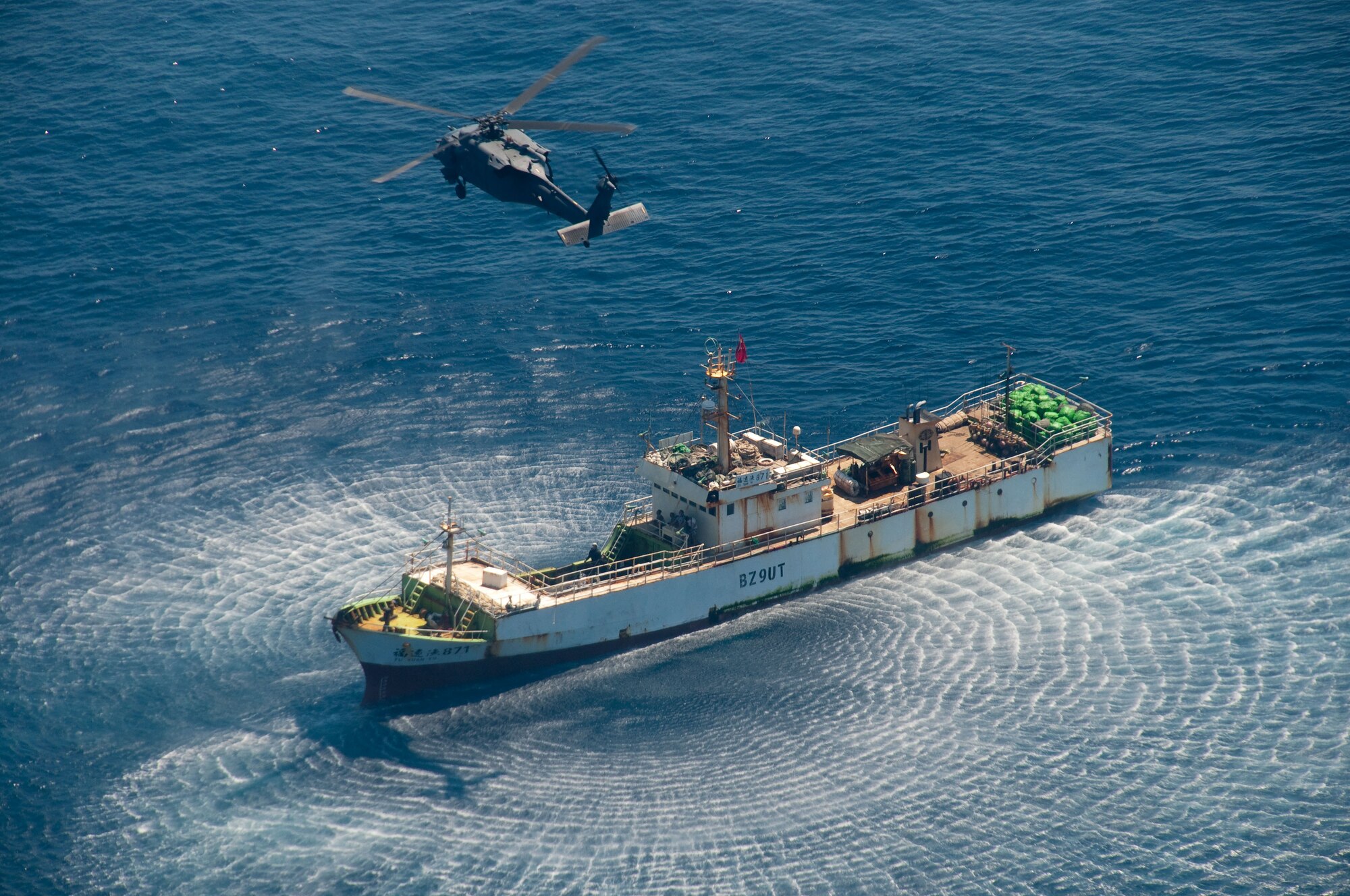 An HH-60G Pave Hawk rescue helicopter from the 129th Rescue Wing hovers over the Chinese fishing vessel Fu Yuan Yu #871, March 12, 2012. Guardian Angel Pararescuemen from the wing rescued two fishermen who were burned in a diesel fire onboard the vessel more than 700 miles off the coast of Acapulco, Mexico. (Air National Guard photo by Maj. Mat Wenthe)