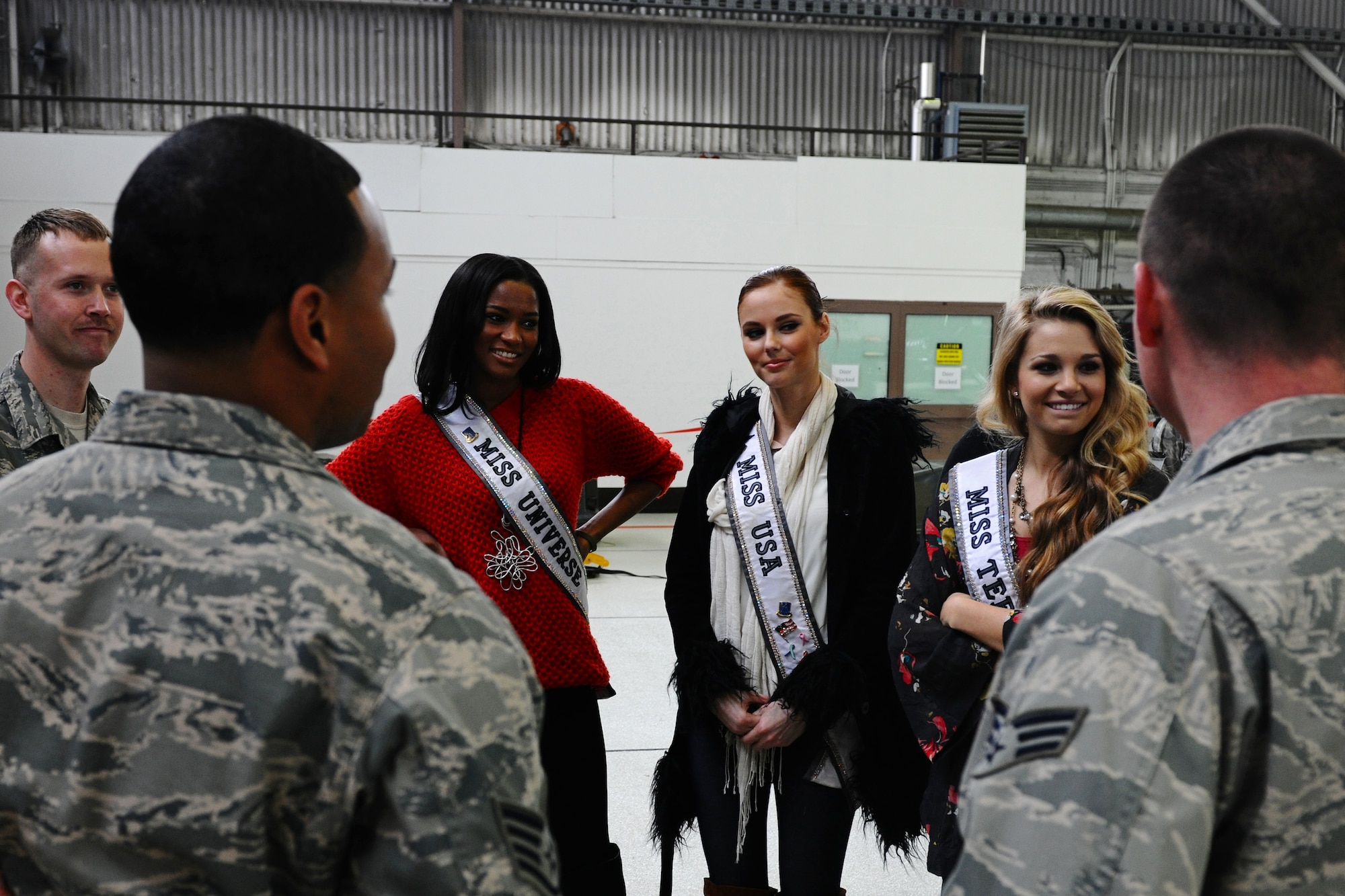 SPANGDAHLEM AIR BASE, Germany – Leila Lopez, Miss Universe 2011, left; Alyssa Campanella, Miss USA 2011, middle; and Danielle Doty, Miss Teen USA 2011, talk with Airman from the 52nd Fighter Wing during their USO and Armed Forces Entertainment tour in Hanger 1 here March 13. The purpose of the tour was to boost morale and show support to U.S. service members and their families stationed in Germany. (U.S. Air Force photo by Airman 1st Class Matthew B. Fredericks/Released)