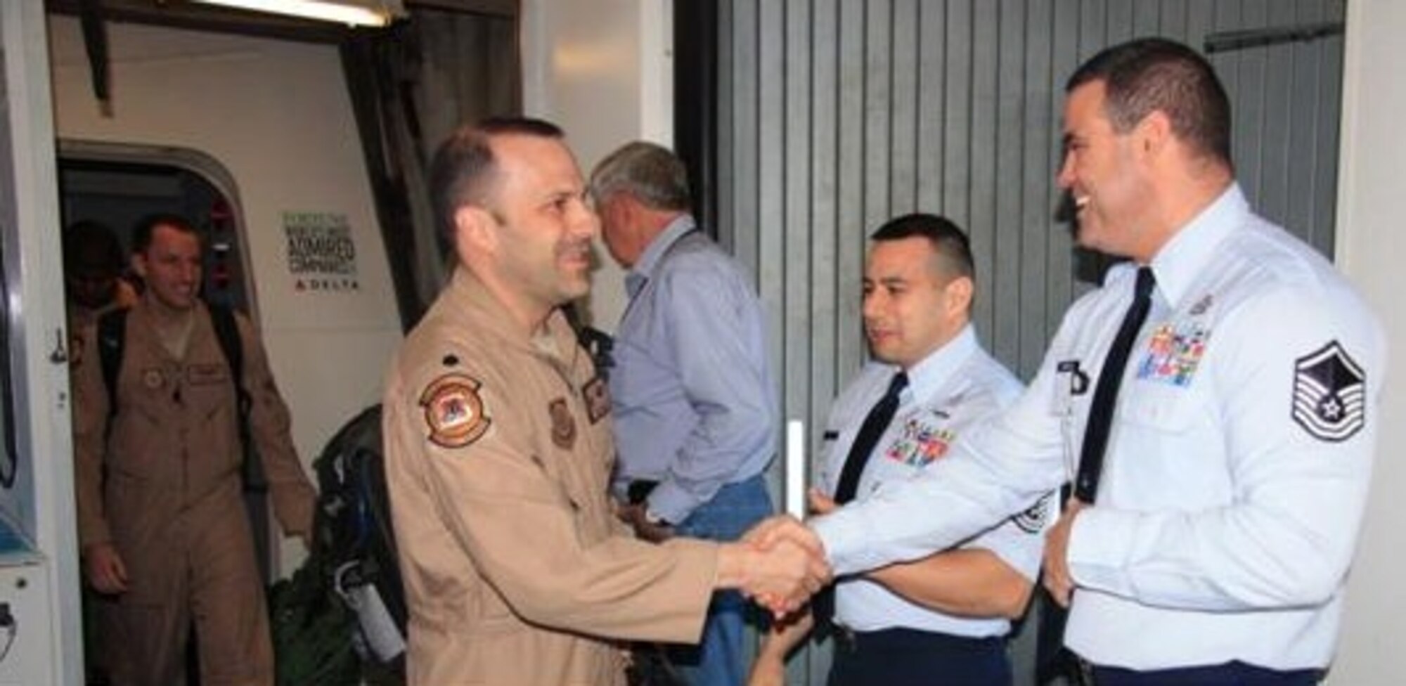 Lt. Col. Doug Hall, 385th Air Expeditionary Group, Det. 1 Commander, and Capt. Tim Rolling, Assistant Director of Operations 385th AEG, Det 1, from the 6th Airlift Squadron, are welcomed home by Senior Master Sgt. Adrian Rivera, 305th Aerial Port Squadron, Det 1, and MSgt David Burdick 305th APS, Det 1. (Air Force photo by Staff Sgt. Rajesh Gohel/Released)