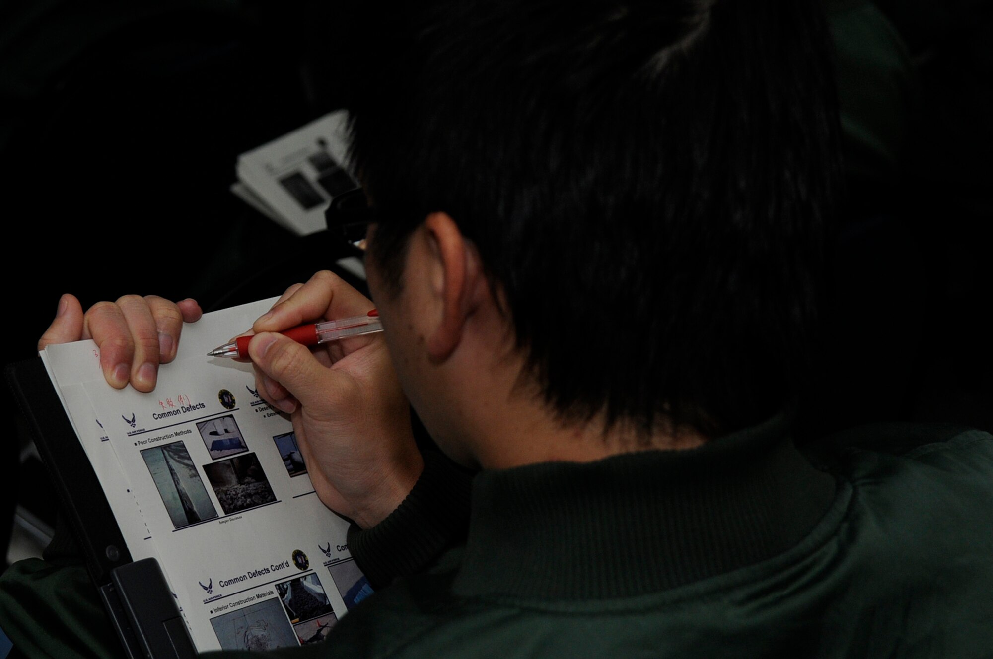 An engineer of the Koku Jieitai, or Japan Air Self-Defense Force, takes notes as a U.S. Air Force Detachment 1, 554th RED HORSE Squadron runway repair class is translated into Japanese on Kadena Air Base, Japan, March 12, 2012. The class taught the Japanese engineers runway crater repair and command and control over the repair operations. (U.S. Air Force photo by Airman 1st Class Tara A. Williamson/Released)