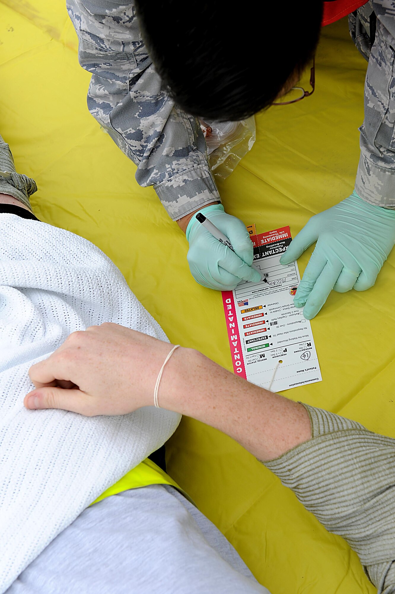 U.S. Air Force Capt. Thomas Hernandez, 18th Medical Group occupational medicine element chief, fills out a patient tag during a local operational readiness exercise training scenario where Airman experienced a bomb explosion on Kadena Air Base, March 14, 2012. Having Airmen with moulage and acting as injured victims allows other Airmen to practice self-aid and buddy care skills. (U.S. Air Force photo by Airman 1st Class Brooke P. Beers/Released)