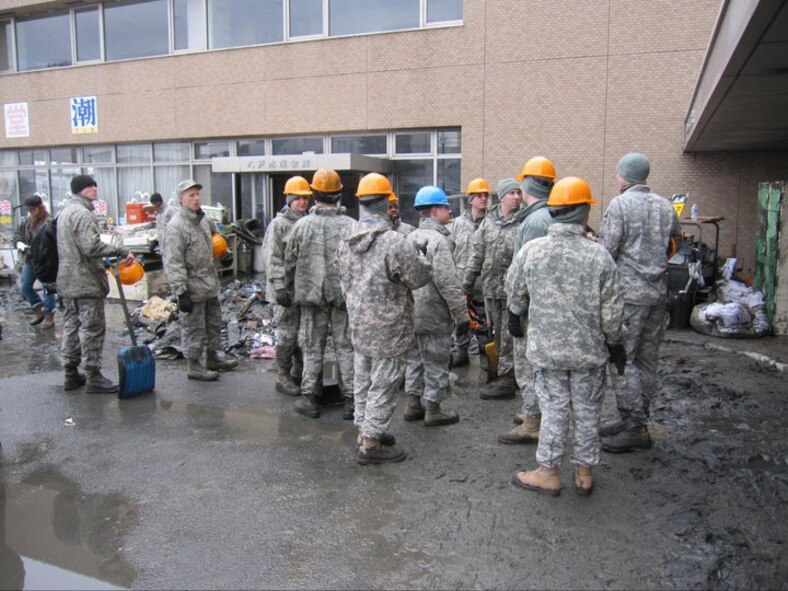 U.S. Air Force Master Sgt. Christopher Burch (with shovel), superintendent of systems engineering division, Misawa Security Operation’s Center, pauses in between clean-up efforts with fellow MSOC service members March 16, 2011, outside the Suisan Kaikan Oshio fisherman’s cafeteria in Hachinohe, Japan. The group from Misawa Air Base, Japan, who helped clear debris from Japan’s 2011 earthquake/tsunami disaster, developed into the Misawa Helps volunteer organization, with help from the base’s Red Cross station. (courtesy photo) 
