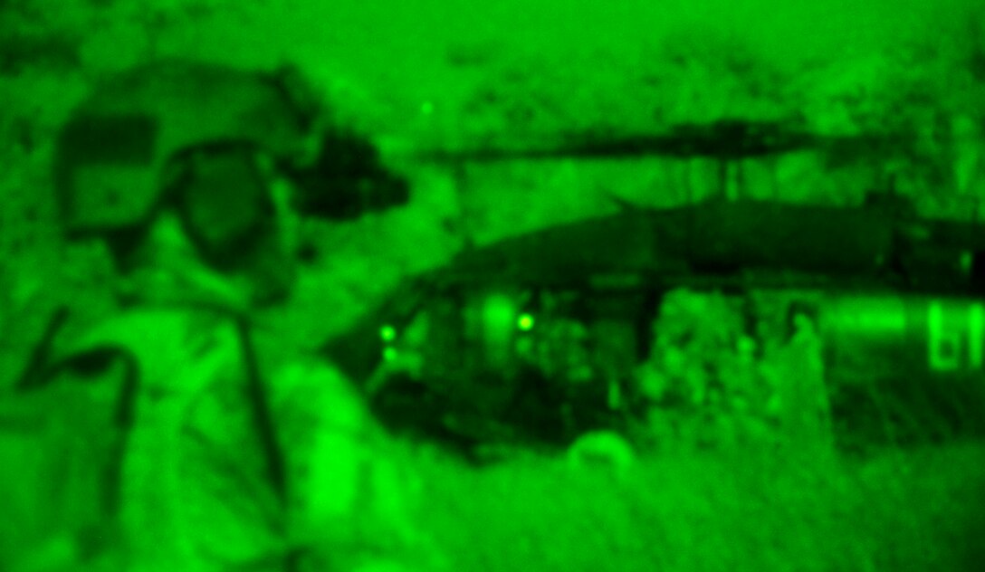 A U.S. special operations forces member uses night vision goggles to scan his sector while Guyanese soldiers exit a UH-60 Black Hawk helicopter during a night time training exercise in Maukuria, Guyana, March 8, 2012.