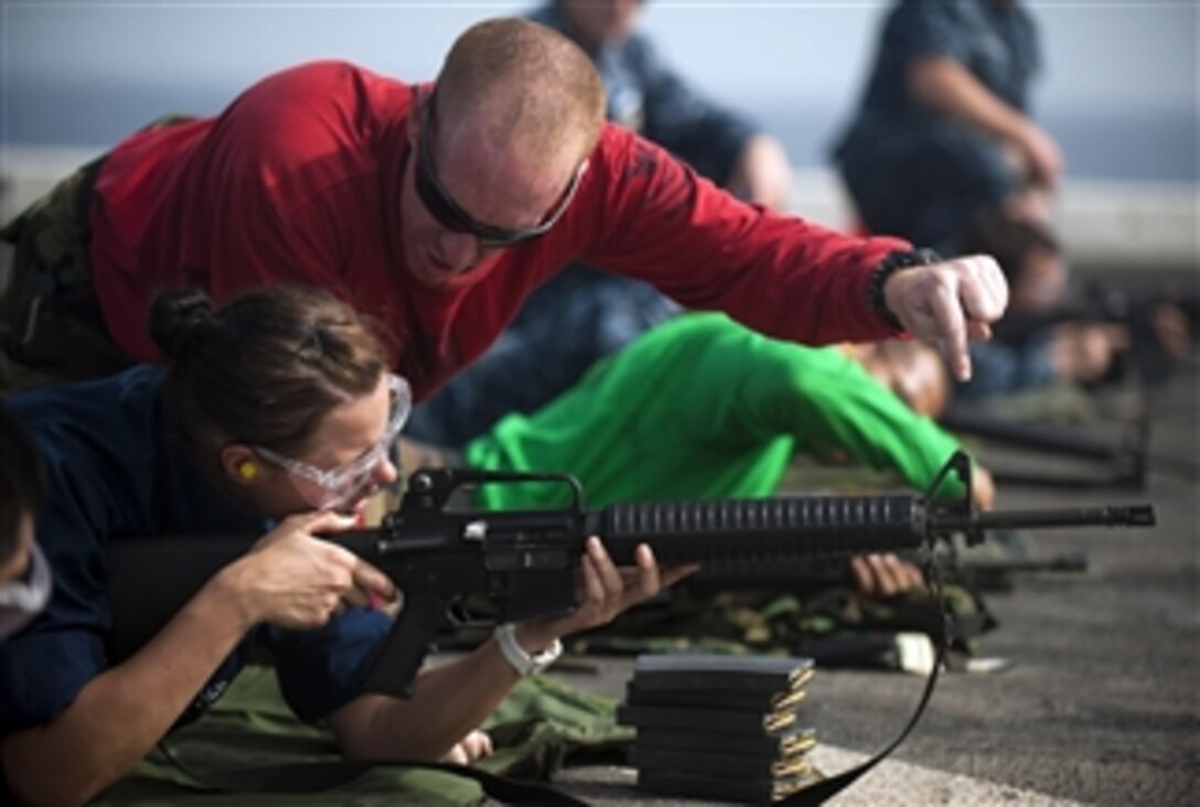 Petty Officer 1st Class Allen Lunn, a line coach, gives Seaman Brittany Koval instruction on how to fire an M-16 service rifle during a live-fire gun qualification exercise aboard the amphibious transport dock ship USS New Orleans (LPD 18) in the Arabian Sea on March 8, 2012.  The New Orleans and embarked Marines assigned to the 11th Marine Expeditionary Unit are deployed as part of the Makin Island Amphibious Ready Group, supporting maritime security operations and theater security cooperation efforts in the U.S. 5th Fleet area of responsibility.  