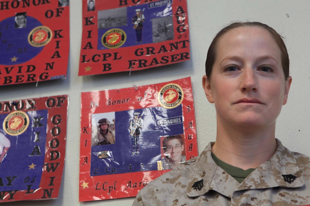 Sgt. Nancy A. Wright, an air support net operator with Marine Air Support Squadron 3, stands in front of the handmade memorials of the Marines that were killed in action from 3rd Battalion, 25th Marine Regiment.  Wright runs marathons in honor of those Marines while displaying an individually dedicated memorial collage on the back of her shirt.
