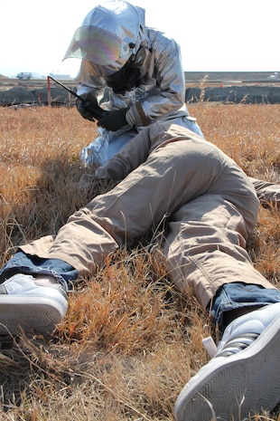 Cpl. Samantha Jones, a Headquarters and Headquarters Squadron Aircraft Rescue Firefighter, calls for help on a radio for a wounded role player during a mass casualty exercise here March 14. The mass casualty exercise was conducted to test ARFF Marine's first response coordination and procedures in the event of an actual mass casualty incident aboard station.