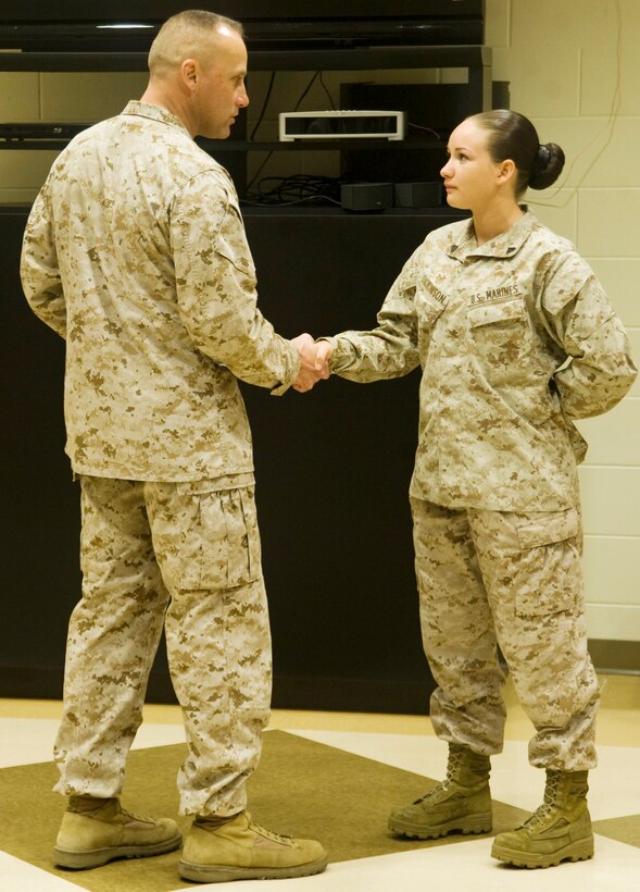 Sgt. Maj. Robert G. VanOostrom presents Cpl. Nicole Dickinson, ammunition technician, Logistics Support Division, MCLB Albany, with a command coin for winning the meritorious corporal board, in front of her peers.