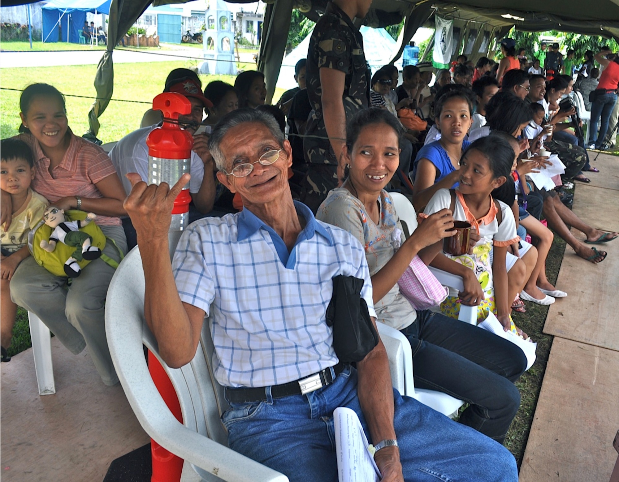 An elderly Filipino patient learns the shaka sign of Aloha while waiting for medical care during Operation Pacific Angel-Philippines on March 6, 2012. PACANGEL is a joint and combined humanitarian mission, which kicked off March 5.  More than 8,500 patients were seen during the six-day mission.  The mission included medical, dental, optometry, engineering support and subject-matter expert exchanges with host nation counterparts. Knowledge gained while working alongside host country agencies and militaries to include non-governmental agencies can be used during any future humanitarian assistance and disaster relief efforts in the Asia-Pacific region.
