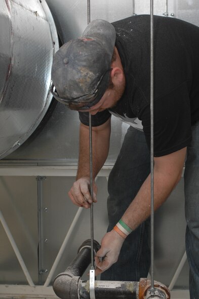 David Hudson, Fire and Sprinkler Services installer, tightens a nut around a hanger on top of a paint booth at the 2nd Maintenance Squadron structural maintenance coating shop on Barksdale Air Force Base, La., March 13. Hudson tightened the nut to make the branch line level with the rest of the installed pipes while installing a new sprinkler system. (U.S. Air Force photo/Airman 1st Class Joseph A. Pagán Jr.)(RELEASED)