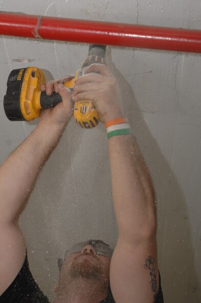 David Hudson, Fire and Sprinkler Services installer, drills a hole in the ceiling at the 2nd Maintenance Squadron structural maintenance coating shop on Barksdale Air Force Base, La., March 13. Hudson made a hole to fit a hanger that will support a branch line for a sprinkler system. (U.S. Air Force photo/Airman 1st Class Joseph A. Pagán Jr.)(RELEASED)