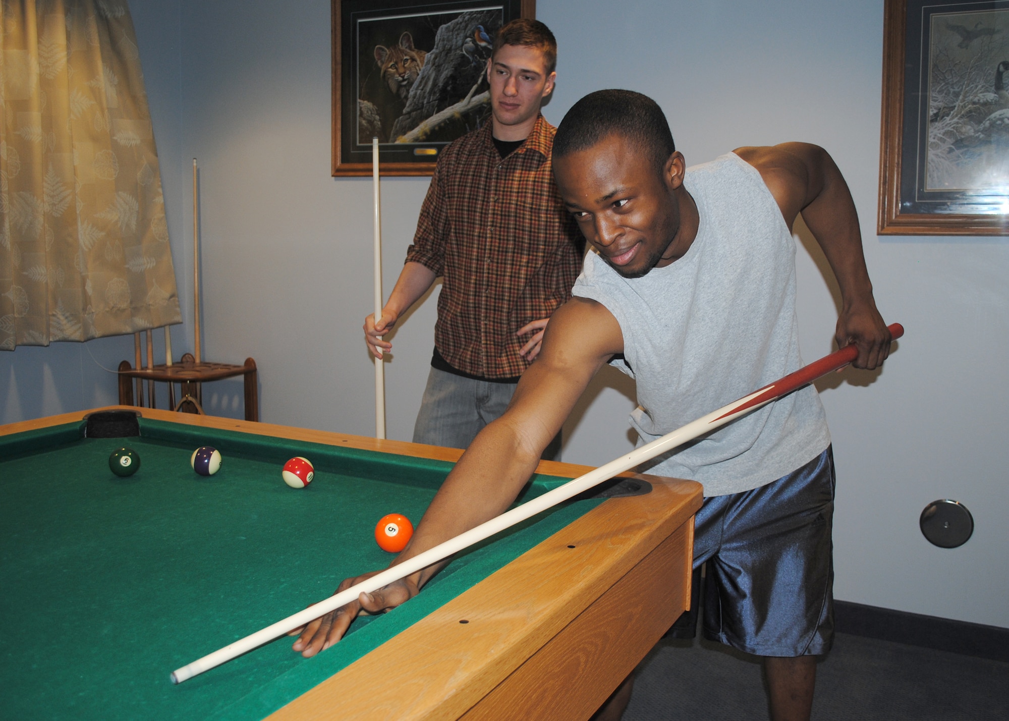 Airman 1st Class Oluwatobiloba Odesanya, right, 341st Logistics Readiness Squadron vehicle equipment apprentice, and Airman Rory Stodgell, 341st LRS traffic management apprentice, play a game of pool in Bldg. 635. Malmstrom Air Force Base's dormitory complex provides its residents multiple dayrooms with cable, television and video game systems.  (U.S. Air Force photo/Airman 1st Class Katrina Heikkinen)