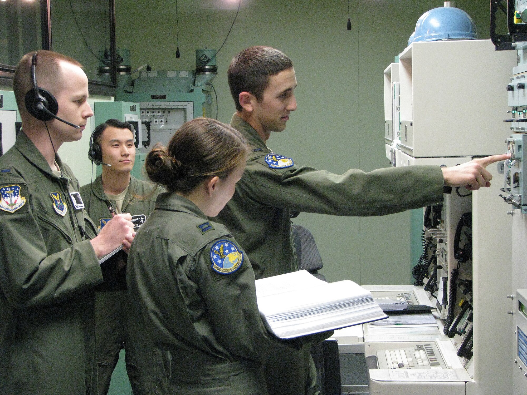 Two 341st Operations Group evaluators conduct a Missile Procedures Trainer evaluation as a 91st Operations Support Squadron crew accomplishes communication check-out procedures. From left to right are 1st Lt. Chris McCollum and 1st Lt. Jarret Ahn, both 341st OG missile combat crew deputy evaluators; Capt. Stephanie Dieterle, 91st Operations Support Squadron missile combat crew commander; and 1st Lt. Zachary Kushner, 91st OSS missile combat crew deputy commander. (U.S. Air Force courtesy photo)