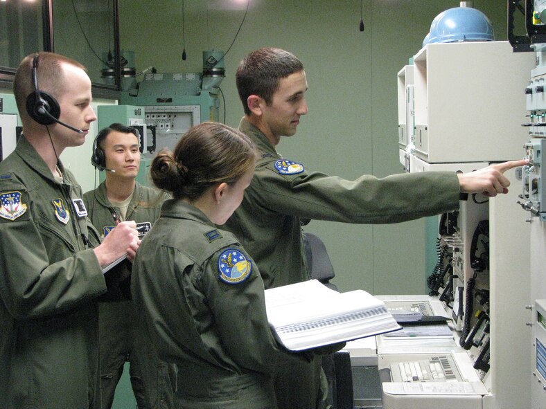 Two 341st Operations Group evaluators conduct a Missile Procedures Trainer evaluation as a 91st Operations Support Squadron crew accomplishes communication check-out procedures. From left to right are 1st Lt. Chris McCollum and 1st Lt. Jarret Ahn, both 341st OG missile combat crew deputy evaluators; Capt. Stephanie Dieterle, 91st Operations Support Squadron missile combat crew commander; and 1st Lt. Zachary Kushner, 91st OSS missile combat crew deputy commander. (U.S. Air Force courtesy photo)