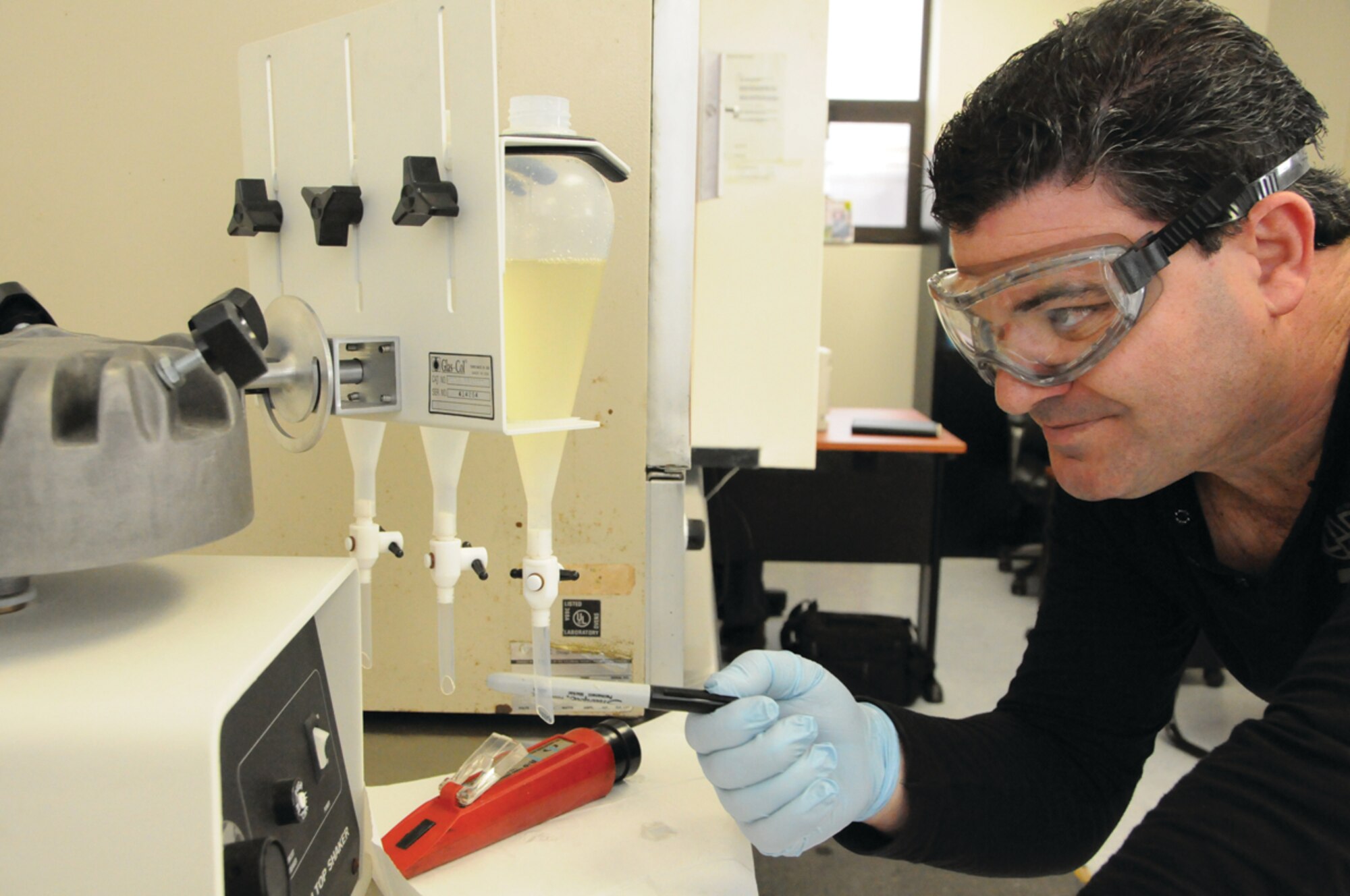 Victor Almeida, 65th Logistics Readiness Squadron, taps on a beaker to get the water to separate from the JP-8 fuel; this tests the particle content of the fuel sample during a monthly fuel check, March 13, 2012.  (U.S. Air Force photo/Tech. Sgt. Chyrece Campbell)