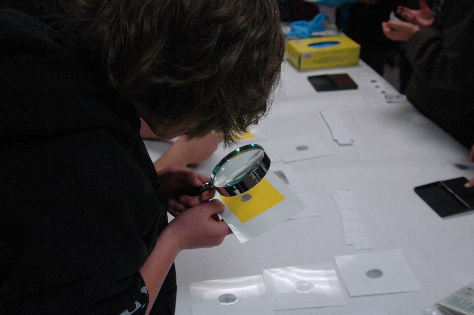 Heston Erickson, a sixth-grade student from Travis Elementary School, attempts to match finger prints found at the mock crime scene Monday in the school’s music room. (U.S. Air Force photo/ Tyler Grimes)