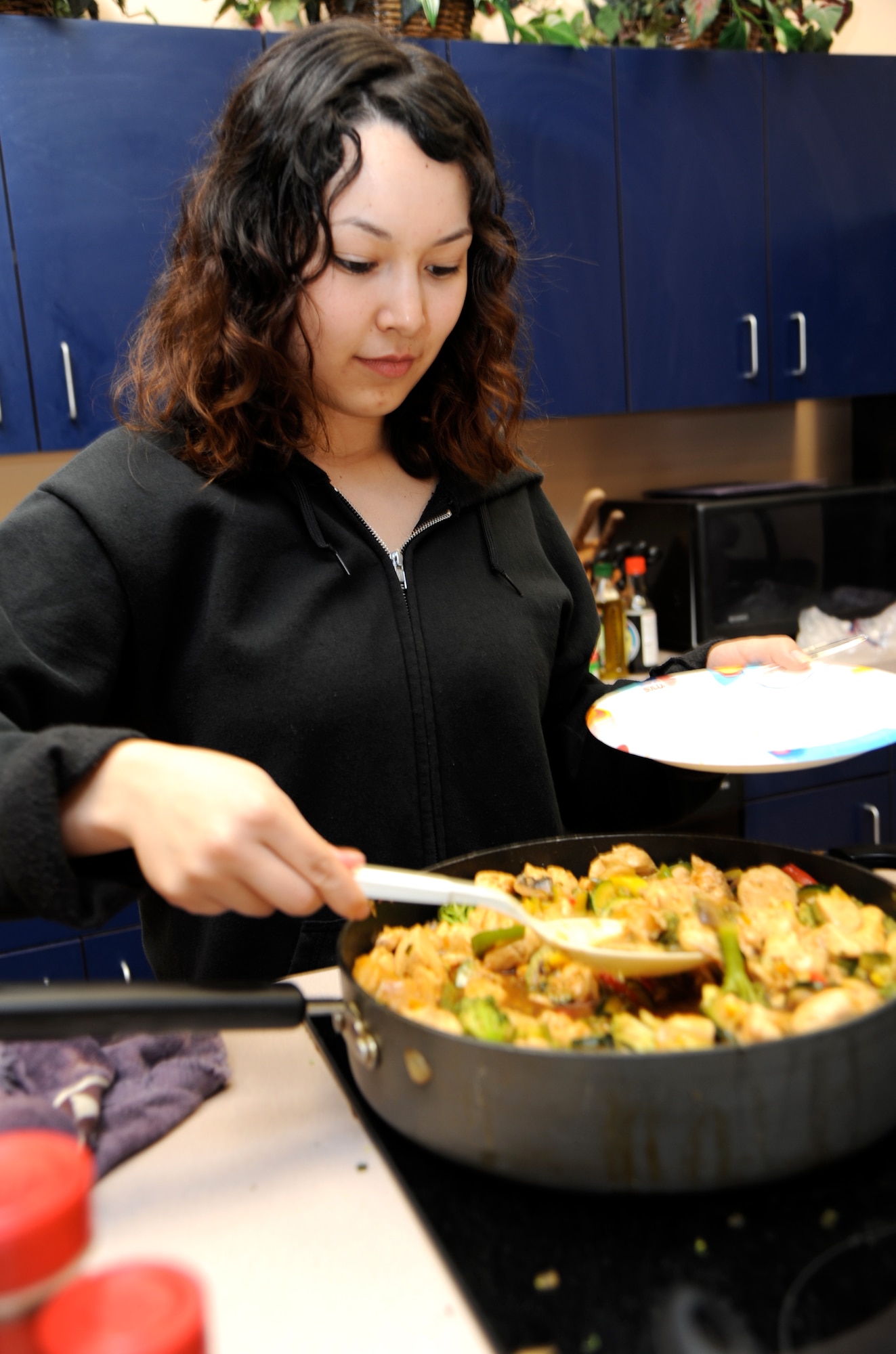 Airman 1st Class Alysia Macedo, an aerospace physiology technician with the 71st Medical Group, helps herself to the chicken vegetable stir fry during a Single-Airman Initiative cooking class held March 12 in the Health and Wellness Center at Vance Air Force Base, Okla. (U.S. Air Force photo/ Airman 1st Class Frank John Casciotta)