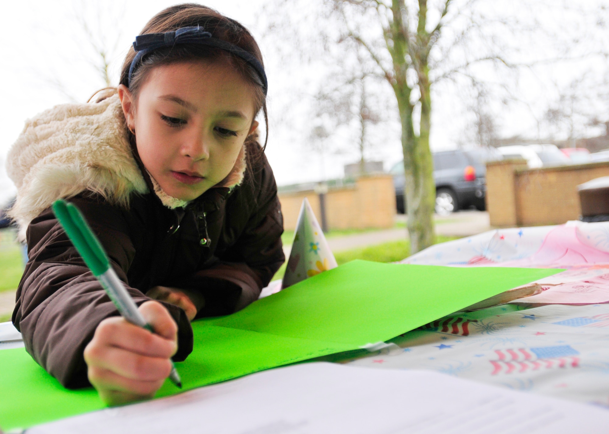 ROYAL AIR FORCE LAKENHEATH, England - Phoenix Stanford, 7, Brownie Girl Scout Troop 004, signs a birthday card during the Girl Scouts' 100th Birthday event at Defender's Park March 12, 2012. The event, planned by the members of Anglia Brownie Troop 43, included a group sing-along, friendship circle, cupcakes and fun. (U.S. Air Force photo by Senior Airman Tiffany M. Deuel)
