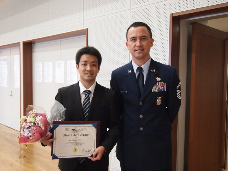 Takashi Umeki, a graduate from the Kadena Language Institute poses for a photo with U.S. Air Force Senior Master Sgt. Manuel Makalena, deputy fire chief of 18th Civil Engineer Group, March 9, 2012, at the Kadena Town Central Community Center, Okinawa, Japan. Umeki won the 18th Wing Best Intern Award while he participated in the annual 18th Wing KLI program that provides student interns with hands-on work experiences in an English-speaking environment.    (Courtesy Photo of Kadena Language Institute)