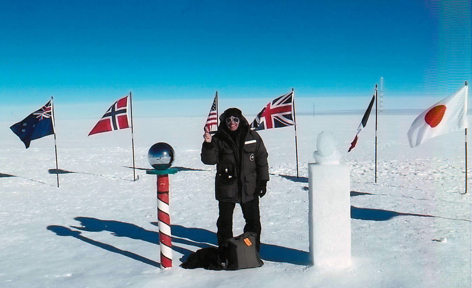 Master Sgt. Scott Terra, 728th Airlift Squadron, Joint Base Lewis-McChord, Wash.,  stands in between the ceremonial South Pole and an ice sculpture of Roald Amundsen, the first human to reach the geographic South Pole.  Terra, a loadmaster, served in an administrative position supporting the 109th Airlift Wing, New York Air National Guard.  His position was part of an effort to expose C-17 Airmen to the LC-130 mission in Operation Deep Freeze. (Courtesy photo)