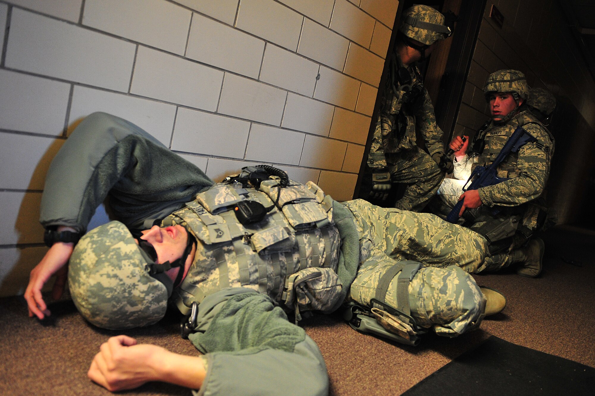 U.S. Air Force Senior Airmen Micheal Krouse and Trent Parrott, 27th Special Operations Security Forces Squadron, communicate with their team as Staff Sgt. Charles East, 27 SOSFS, lies on the ground simulating a casualty during an active shooter training scenario at Cannon Air Force Base, N.M., March 1, 2012. Training scenarios provide a safe and controlled environment to practice different tactics, techniques and procedures. (U.S. Air Force photo by Tech. Sgt. Josef Cole)