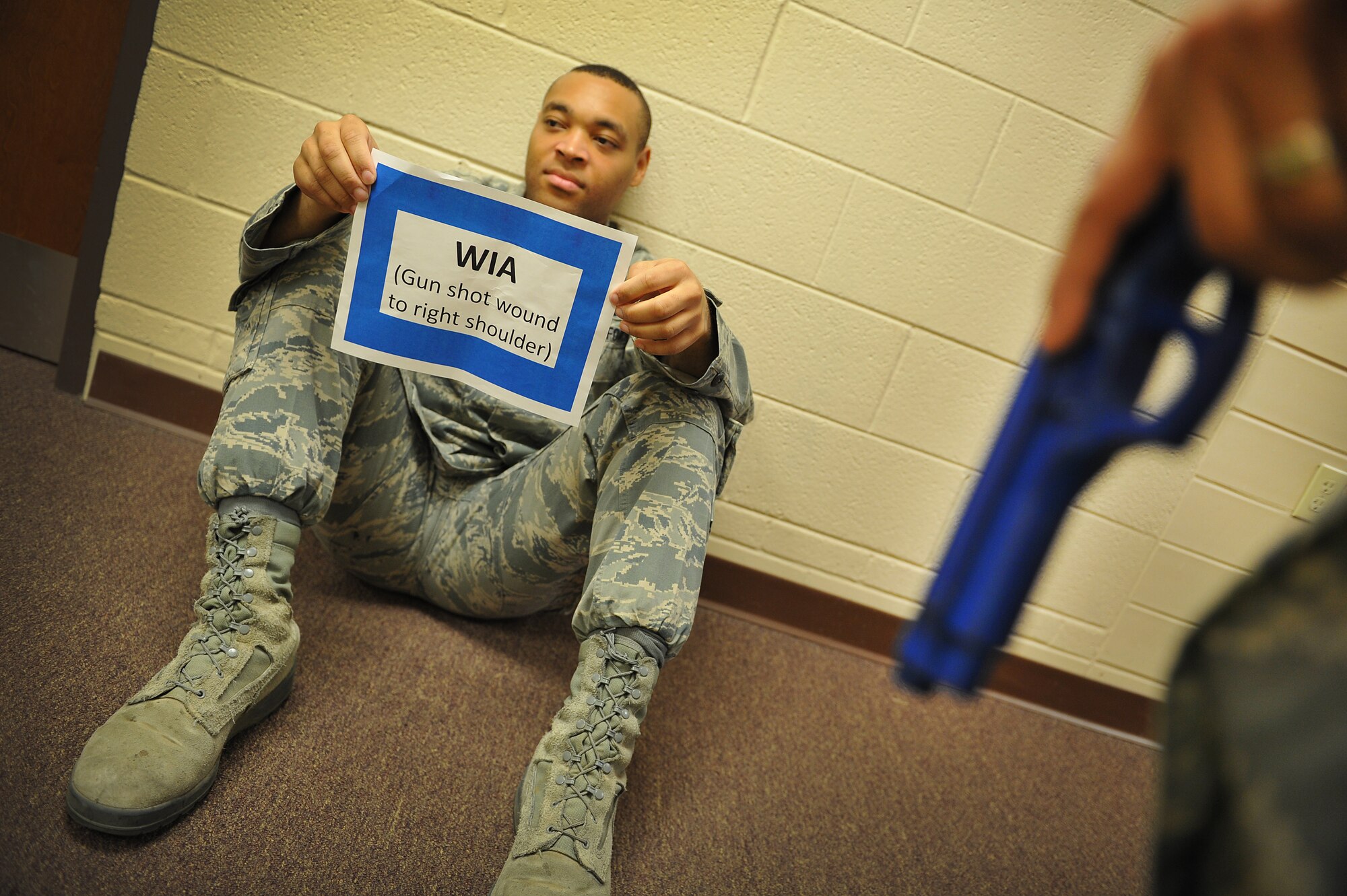 U.S. Air Force Airman 1st Class Dorian Young, 27th Special Operations Logistics Readiness Squadron, holds a sign during an active shooter training scenario at Cannon Air Force Base, N.M., simulating he is a wounded victim, March 1, 2012. Training scenarios provide a safe and controlled environment to practice different tactics, techniques and procedures. (U.S. Air Force photo by Tech. Sgt. Josef Cole)