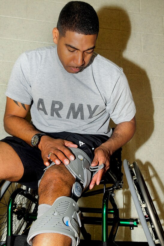 U.S. Army Sgt. Hilton Hunter, Warrior Transition Unit, adjusts the straps on his unloaded brace before the start of his physical training basketball session at the McClellan Fitness Center, March 9, 2012. Hunter participates in adaptive sports and modified PT to help smooth out his recovery both mentally and physically after sustaining injuries in Afghanistan. (U.S. Air Force photo by Staff Sgt. Ashley Hawkins/Released)