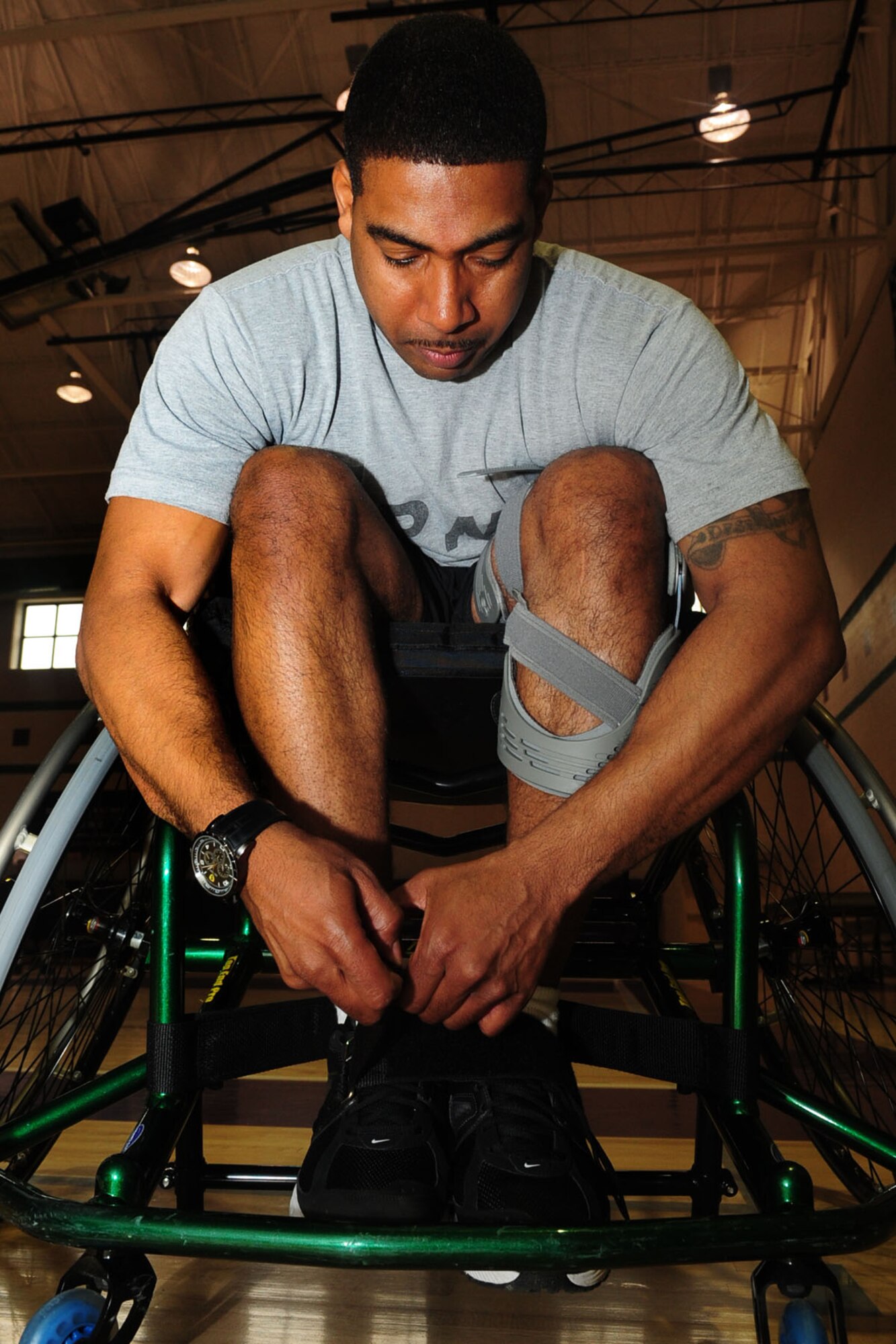 U.S. Army Sgt. Hilton Hunter, Warrior Transition Unit, straps into his wheelchair before the start of his physical training basketball session at the McClellan Fitness Center, March 9, 2012. Hunter was injured in Afghanistan in Feb. 2011, which brought him into the Eustis Warrior Transition Unit for treatment, and ultimately into adaptive sports. (U.S. Air Force photo by Staff Sgt. Ashley Hawkins/Released)
