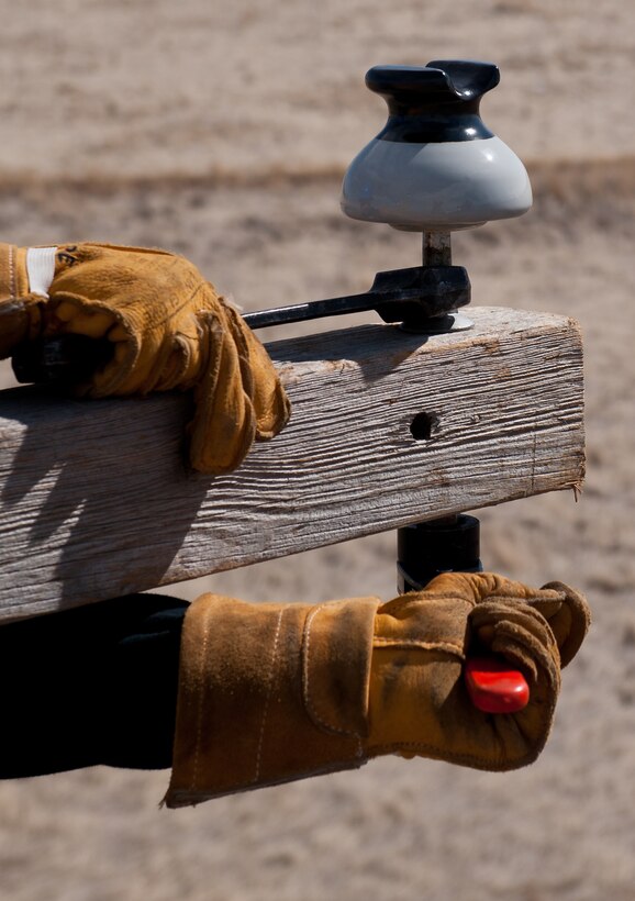 Airman 1st Class Alex Price, 28th Civil Engineer Squadron electric lineman, tightens an insulator onto a cross-section of a new utility pole during an equipment upgrade at the base Electric Shop’s training site on Ellsworth Air Force Base, S.D., March 13, 2012. During training, electrical lineman must install a cross-section and three insulators to replicate a regulation electrical pole in order to stay proficient and qualified to perform these tasks. (U.S. Air Force photo by Airman 1st Class Kate Thornton/Released)
