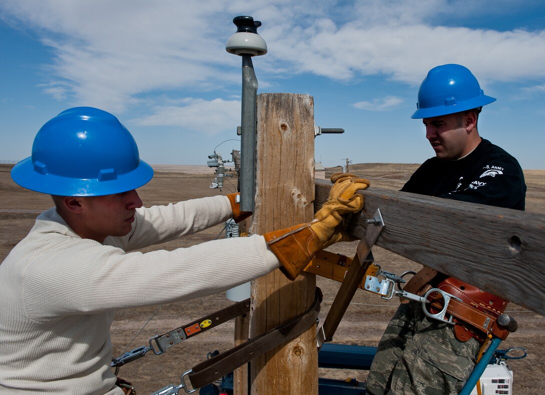 Airmen 1st Class Patrick Garrett, left, and Alex Price, 28th Civil Engineer Squadron electric linemen, position a cross-section onto a new utility pole during an equipment upgrade at the base Electric Shop’s training site on Ellsworth Air Force Base, S.D., March 13, 2012. The training site provides 28th CES Airmen with a safe training environment where they can practice tasks related to a variety of electrical equipment and installation techniques. (U.S. Air Force photo by Airman 1st Class Kate Thornton/Released)