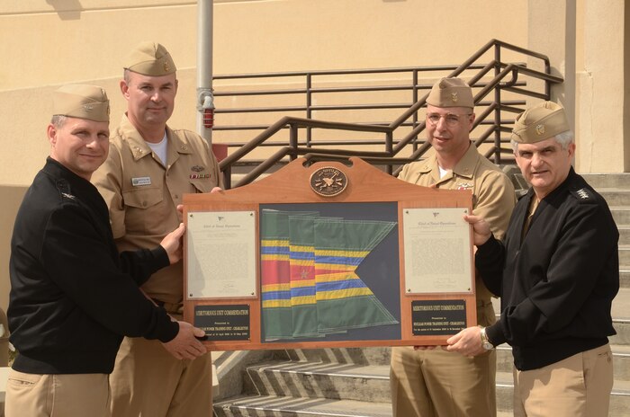 Admiral Kirk Donald presents the Meritorious Unit Commendation to Capt. Dennis White during a ceremony at the Nuclear Power Training Unit at Joint Base Charleston - Weapons Station March 8. NPTU received the MUC for the period Sept. 1, 2008 to Dec.16, 2011. During that time, NPTU certified the majority of the nuclear operators reporting to the United Sates nuclear fleet and conducted three open ocean tows of the moored training ships and conducted planning and preparations for a site facilities expansion. Admiral Donald is the director of Naval Reactors and Captain White is the NPTU Charleston Commanding Officer. Also pictured are Master Chief Petty Officer Wayne Robbins, NPTU Command Master Chief (second from left) and Master Chief Petty Officer Donald Ziegler, the incoming NPTU Command Master Chief. (U.S. Air Force photo/Tech. Sgt. Chrissy Best)