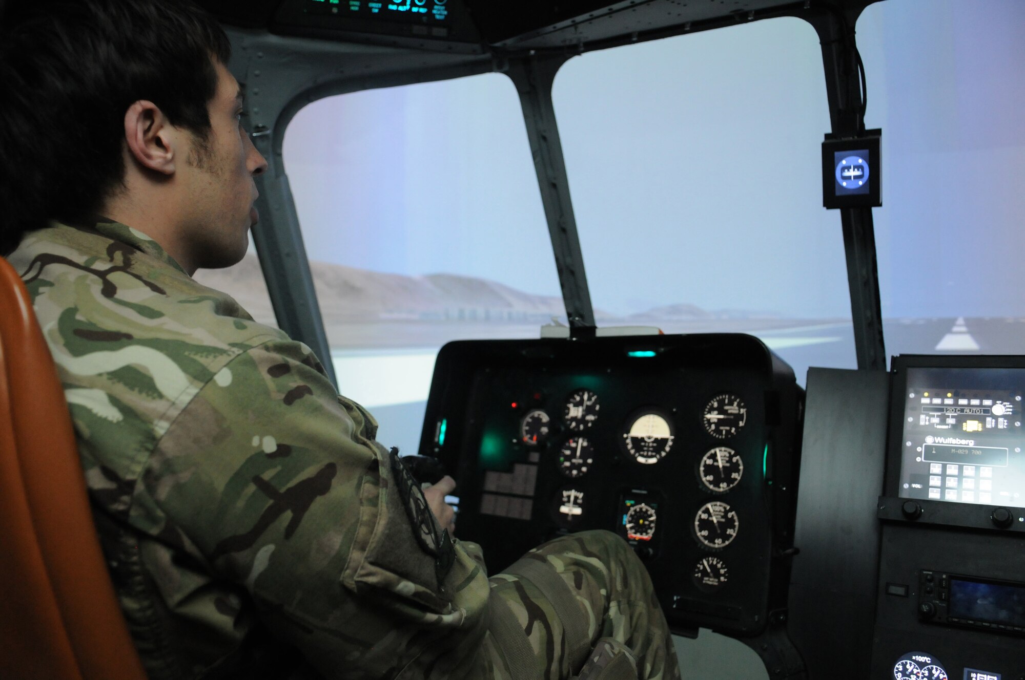 Royal Air Force Flight Lt. Tom Loucaides, 438th Air Expeditionary Wing Thunder Lab director of aviation training, demonstrates a take-off in an Afghan air force Mi-17 helicopter simulator during a familiarization training session, Kabul International Airport, Afghanistan, March 15, 2012. Loucaides explained the different functions a pilot must perform to include hovers, lateral and forward directional movements, and the basic control functions to U.S. Navy Petty Officer 1st Class Robert Hay, who will assist in training afghan pilot candidates through approximately 60 hours of academic instruction as well as flight screening in the Cessna 182T prior to beginning flight training. (U.S. Air Force photo by Staff Sgt. Nadine Y. Barclay)