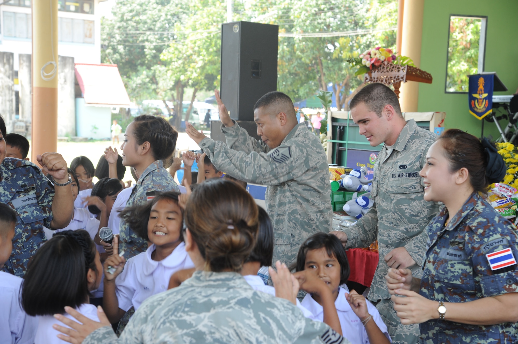 Master Sgt. Jason Adkins (center), Cope Tiger Customs liaison officer from Headquarters Pacific Air Forces, Joint Base Pearl Harbor-Hickam, Hawaii, and Airman 1st Class Thomas Fitzgerald (right), Cope Tiger F-15 Eagle crew chief from the Florida National Guard's 125th Fighter Wing, Jacksonville, Florida, dance with children curing a community outreach and cultural exchange event, Mar. 13. The Airmen were at the Watprommarat School, which was visited by more than 40-Airmen from the U.S. Air Force, Republic of Singapore Air Force, and exercise host, Royal Thai Air Force. The Airmen are participating in exercise Cope Tiger, a large force air employment exercise designed to enhance readiness and interoperability among participating nations in the Asia-Pacific region. (U.S. Air Force Photo/Capt. David Herndon)