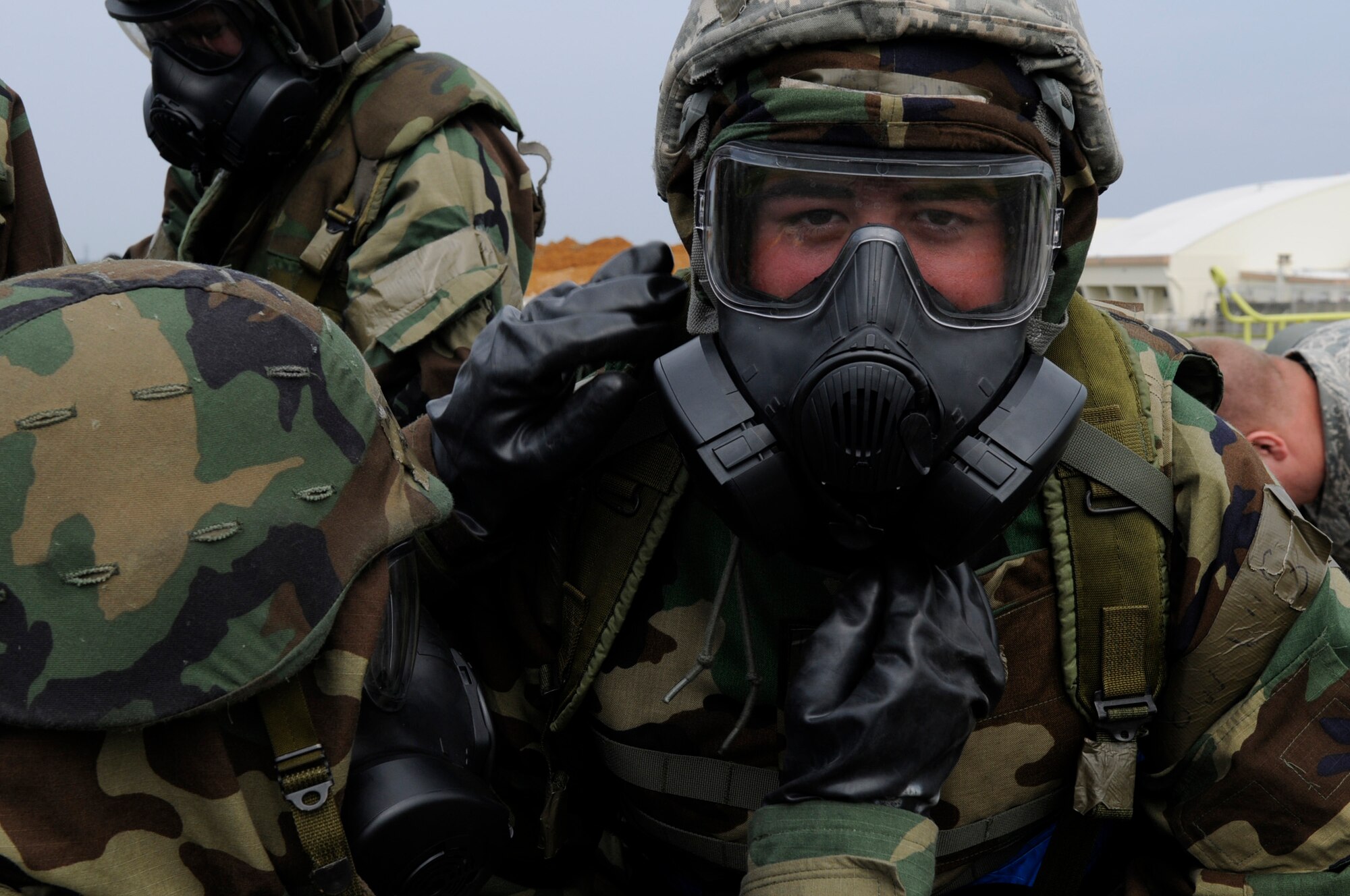 Airmen perform buddy checks to guarantee all skin is covered when donning protective equipment during local operational readiness exercise Beverly High 12-3 on Kadena Air Base, Japan, March 16, 2012. If skin is open to the air during a chemical attack, Airmen risk contaminating themselves and others around them. (U.S. Air Force photo by Airman 1st Class Tara A. Williamson/Released)