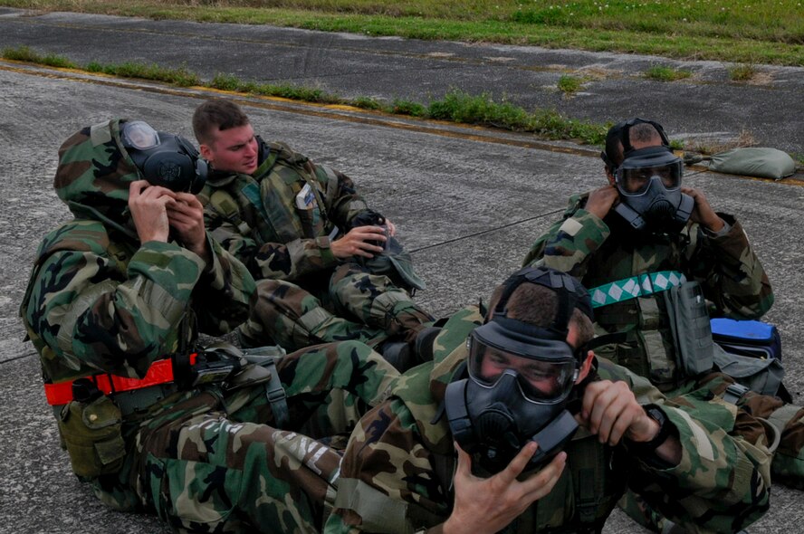 Airmen don gas masks and gloves in a scenario to ensure all skin is covered during a simulated nerve agent attack as part of local operational readiness exercise Beverly High 12-3 on Kadena Air Base, Japan, March 16, 2012. Securing the hood underneath the chin to protect the neck is an important part of the protective equipment worn during LOREs. (U.S. Air Force photo by Airman 1st Class Tara A. Williamson/Released)