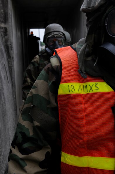Airmen check around the building after a base attack scenario to look for any foreign objects or traces of chemical agents during local operational readiness exercise Beverly High 12-3 on Kadena Air Base, Japan, March 15, 2012. Training in-house allows Airmen to practice readiness skills in a safe environment to prepare for real world contingencies. (U.S. Air Force photo by Airman 1st Class Tara A. Williamson/Released)