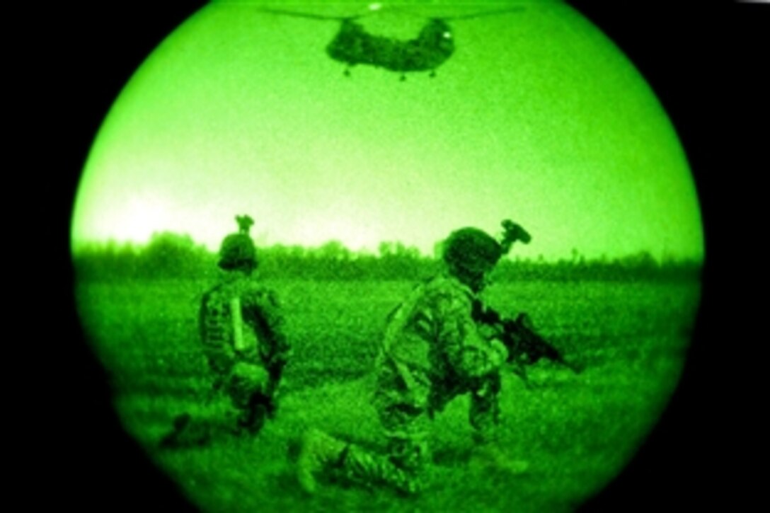 As seen through a night-vision device, soldiers conduct a night raid mission and provide security as a CH-47 Chinook helicopter circles overhead during exercise Emerald Warrior near Hattiesburg, Miss., March 5, 2012.