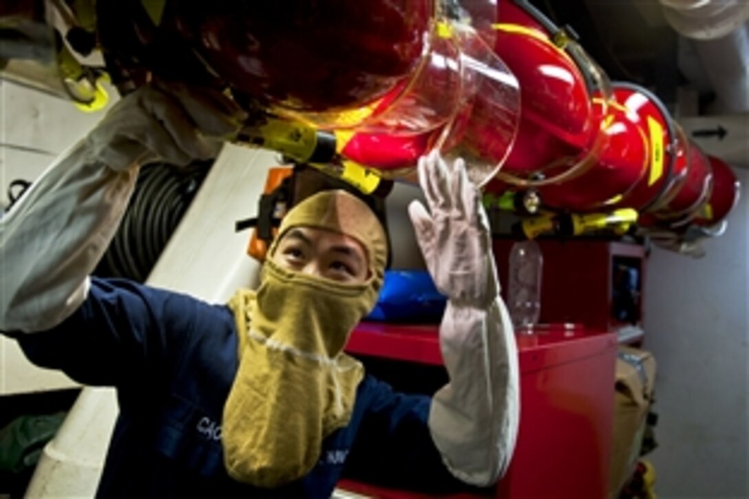 U.S. Navy Seaman Willie Cao inspects flashlights on firefighting helmets during a general quarters exercise aboard the aircraft carrier USS Enterprise in the Atlantic Ocean, March 15, 2012. The Enterprise is conducting its final deployment to support maritime security operations and theater security cooperation efforts in the U.S. 5th and 6th Fleet areas of responsibility. Cao is a machinist's mate fireman.